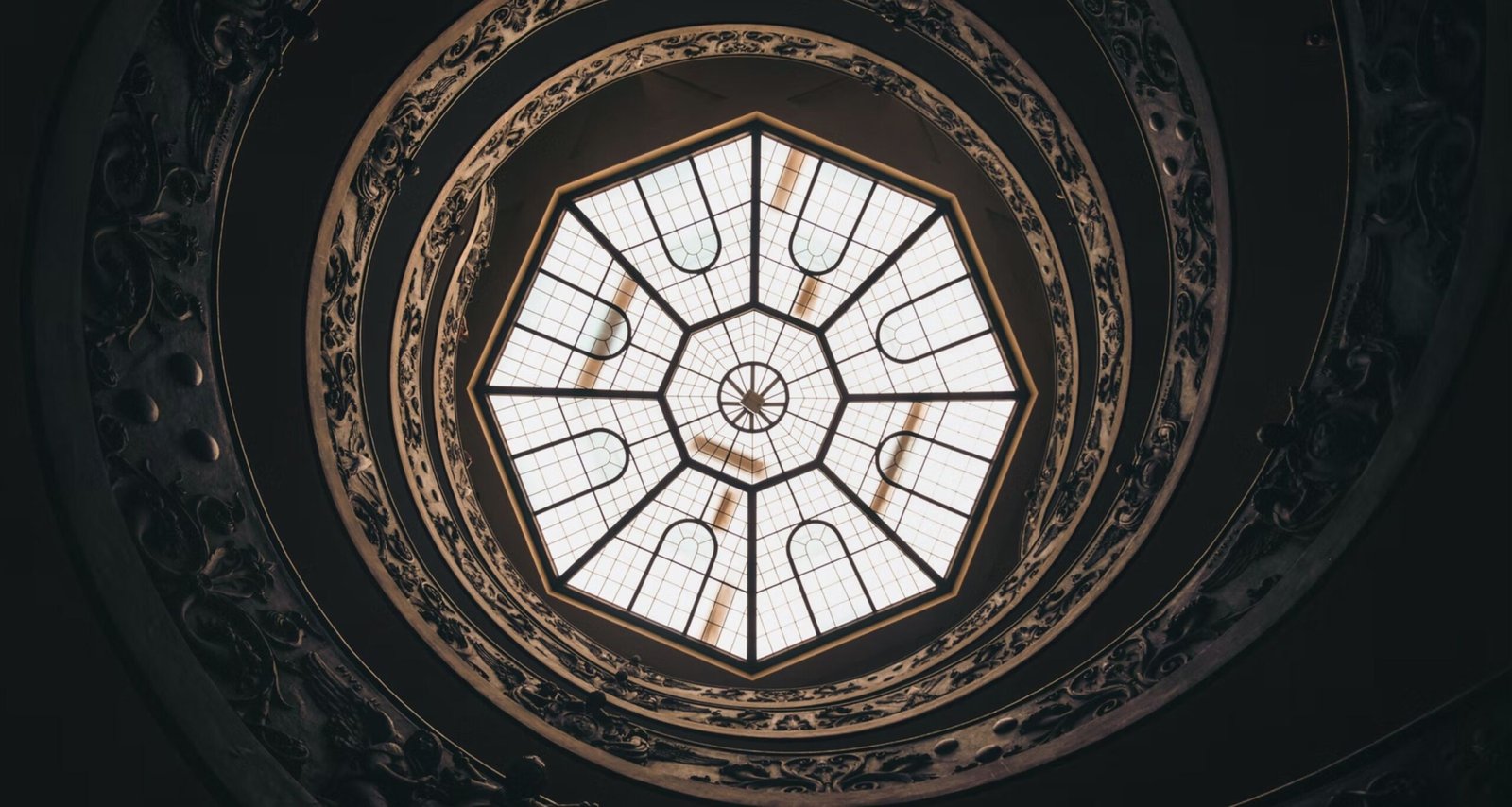 Hebras Avocats. Verrière octogonale vue du dessous, cernée par la rampe ornementée d'un escalier hélicoïdal.