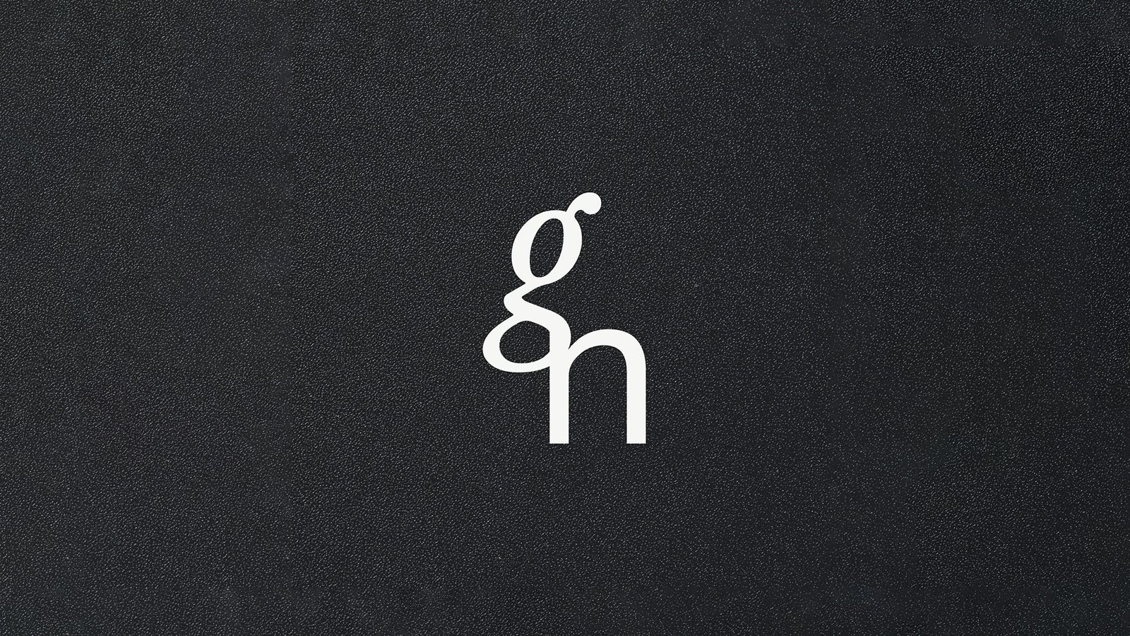 Monogramme de Griffon Noir : un g italique et un n droit entrelacés, en blanc cassé sur un fond noir texturé.