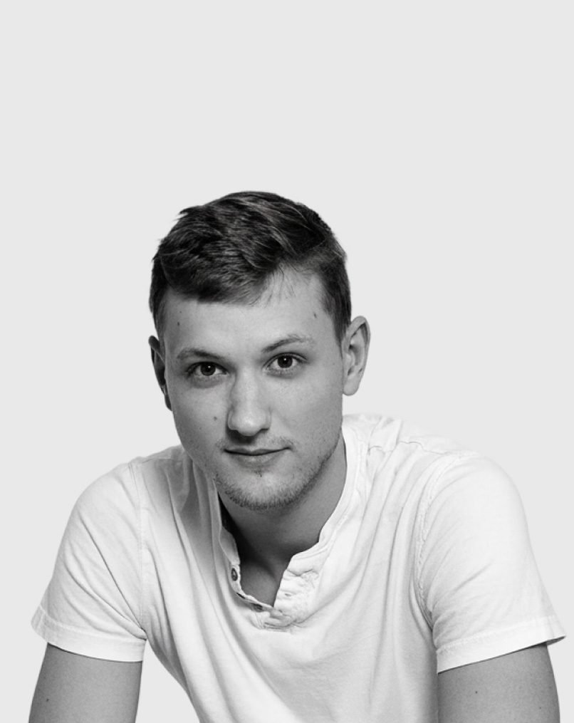 Portrait en noir et blanc d'Eric Huguenin, en t-shirt clair sur fond gris.